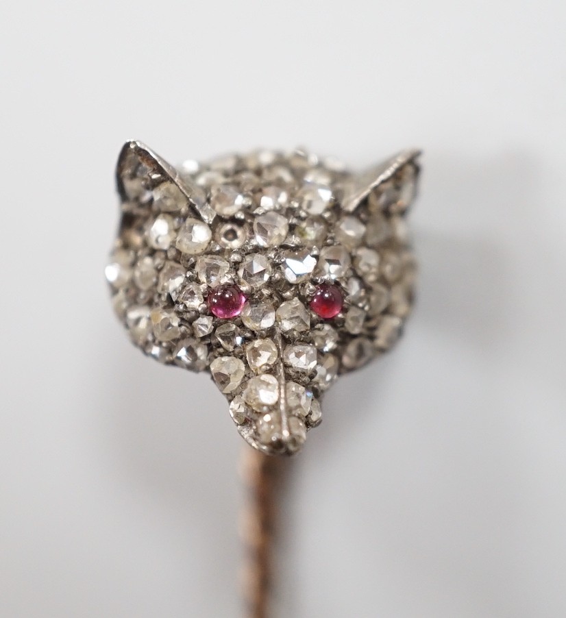 A late Victorian yellow and white metal, cabochon ruby? and rose cut diamond set fox head stick pin, 56mm, gross weight 4.7 grams (two stones missing).